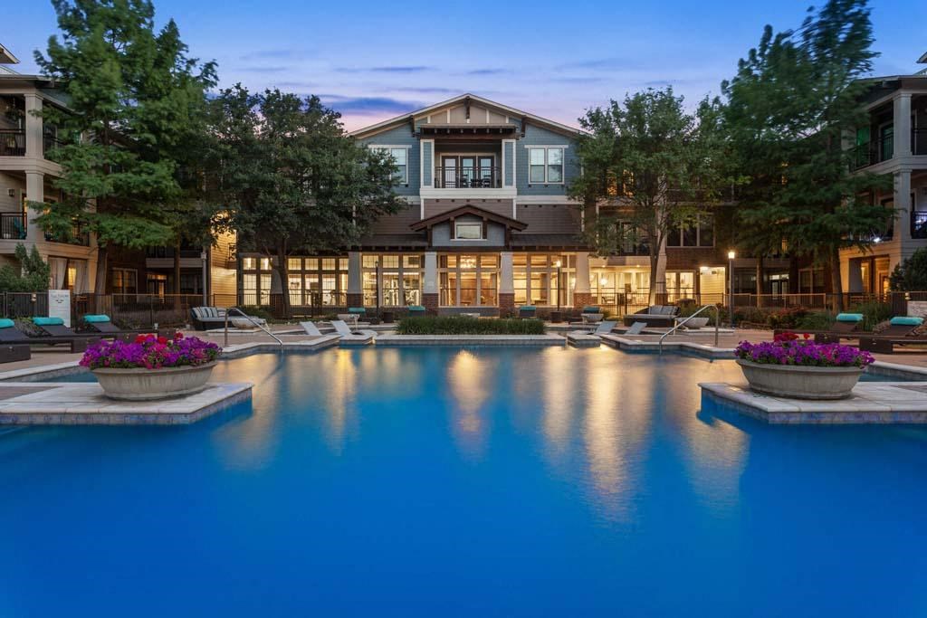a large swimming pool in front of a hotel at dusk