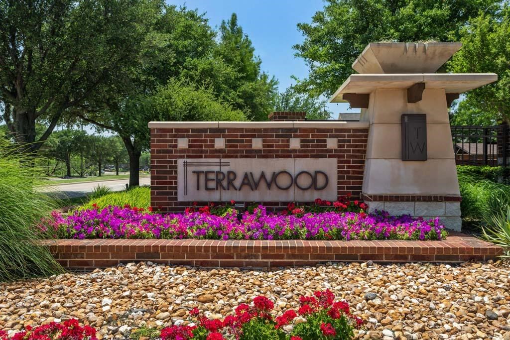a sign for terra nova at the front of a garden of flowers