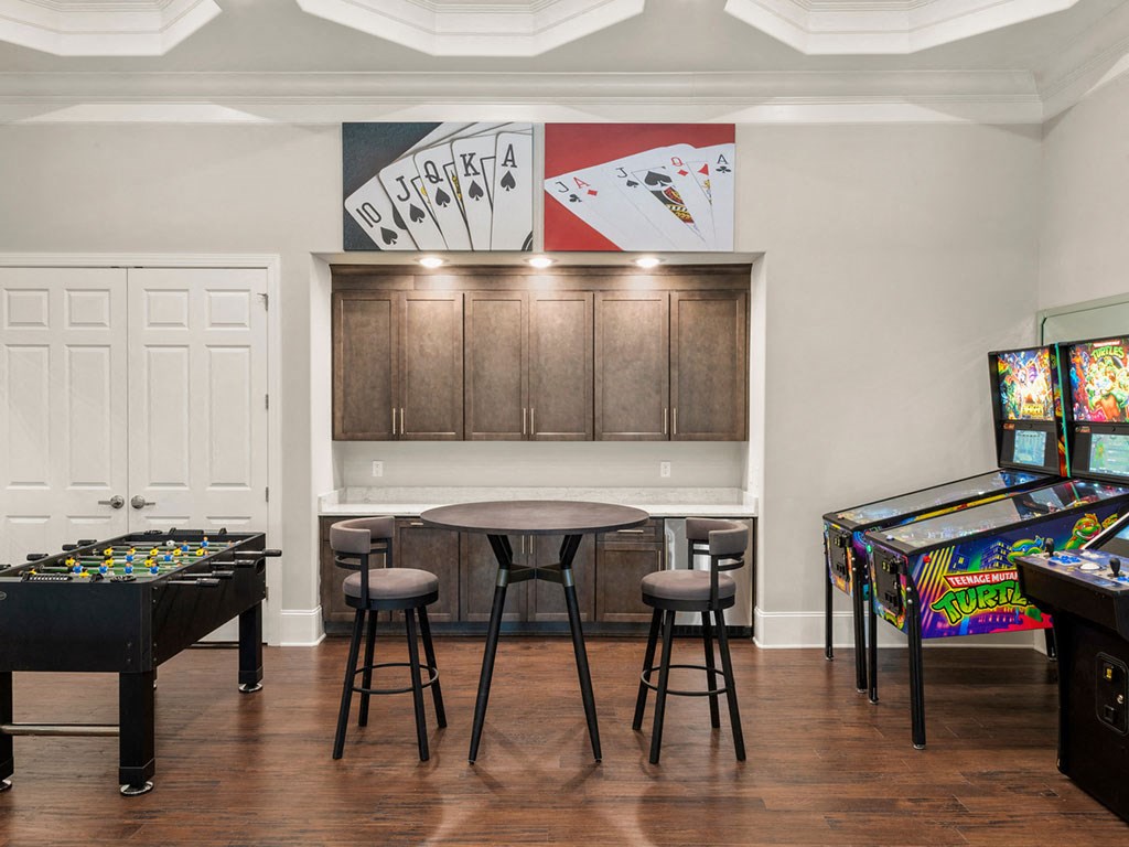 A room with a pool table, air hockey table, and a bar area.