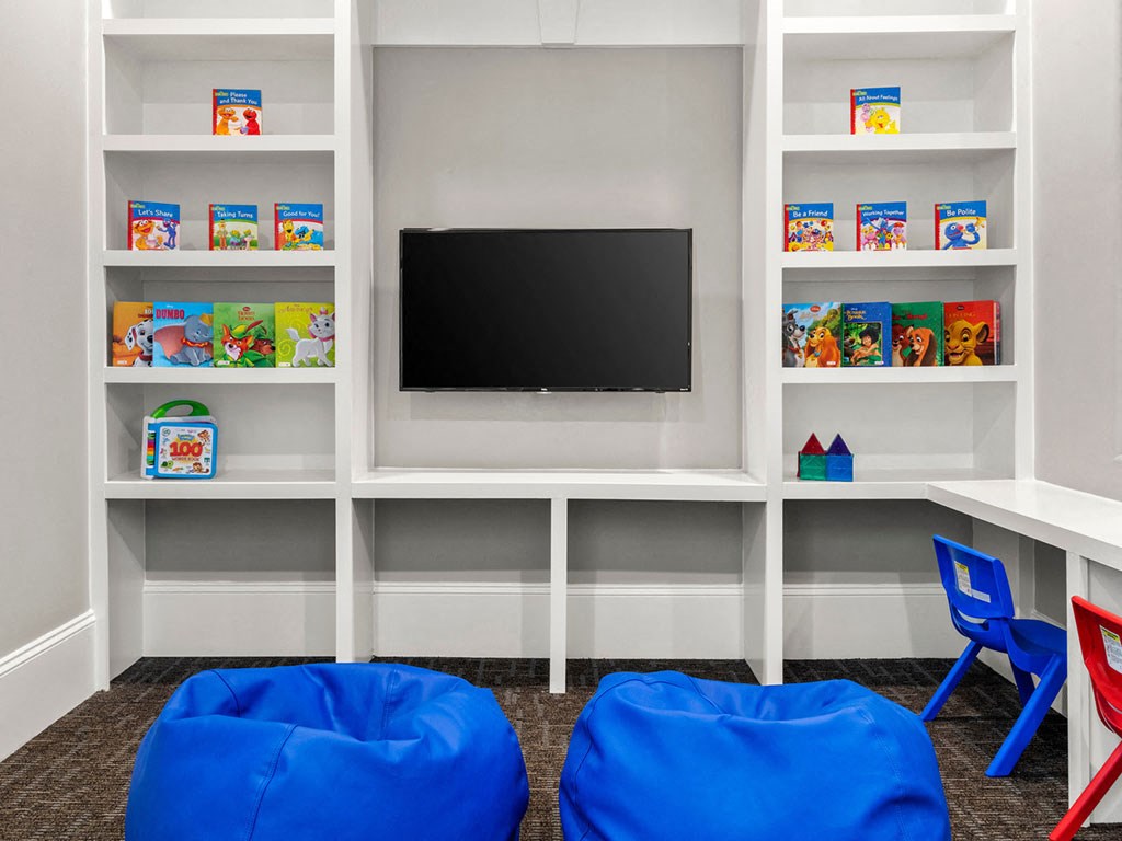 A white shelving unit with a flat screen TV mounted on the wall and toys on the shelves.