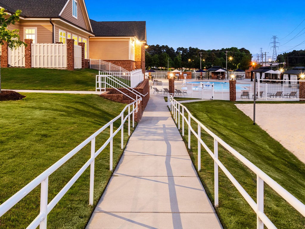 A white fence runs along a concrete walkway.