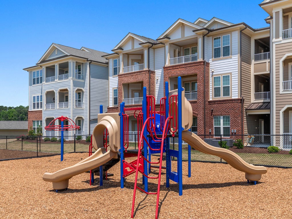 A playground with a slide in front of apartment buildings.