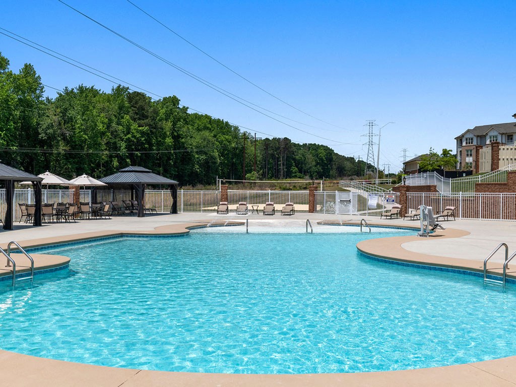 A large swimming pool surrounded by a fence and trees.