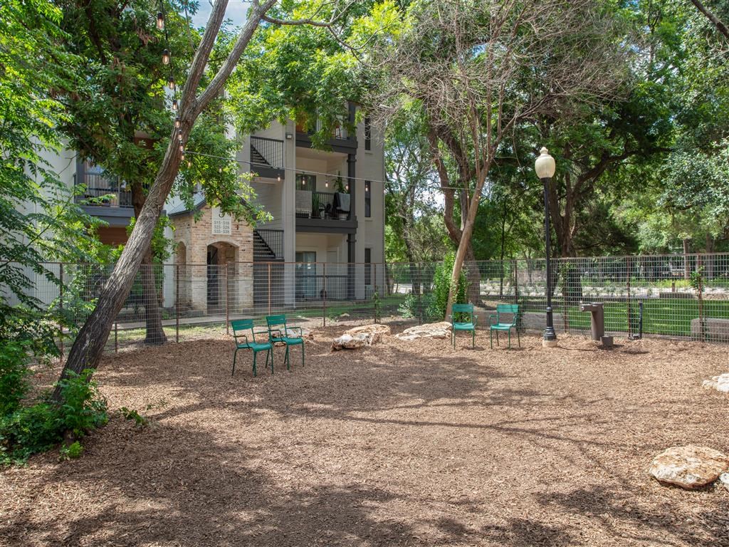 a playground with chairs and trees in front of an apartment building
