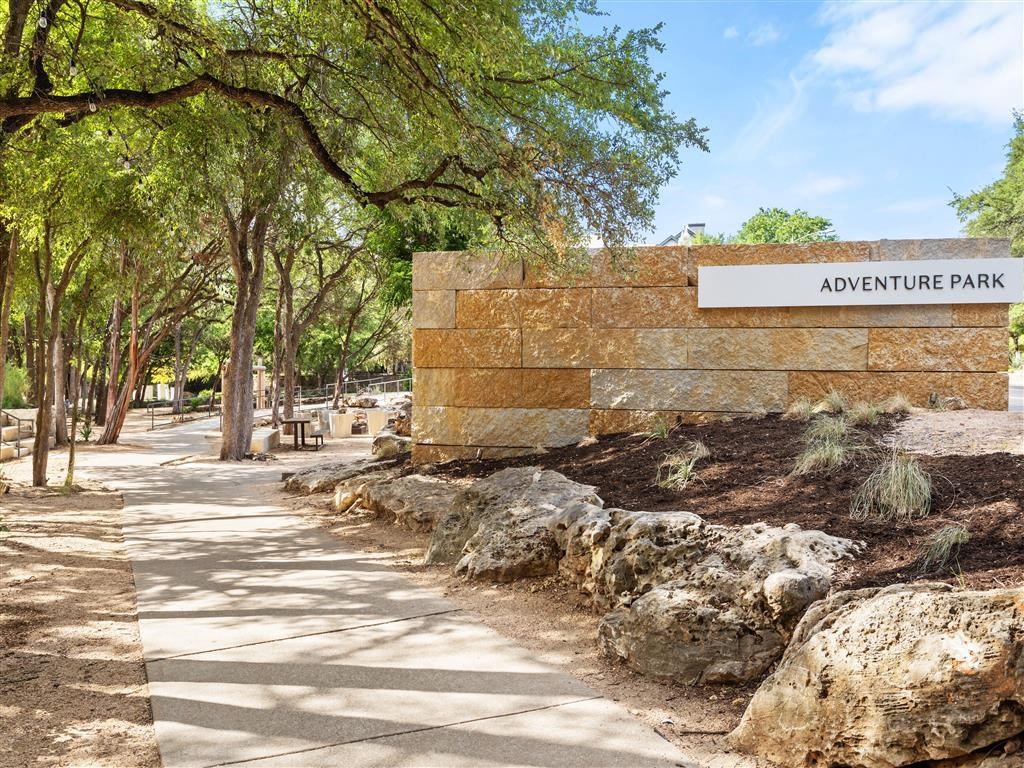 a sign for adventure park in front of a stone wall