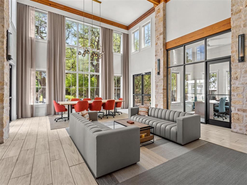 a living room with couches and chairs and large windows