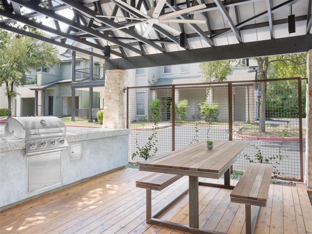 a patio with a picnic table and a grill