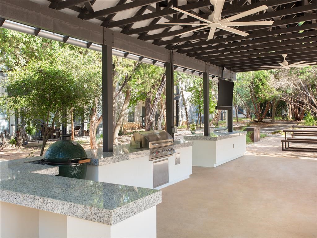the outdoor kitchen is under a roof with trees and benches