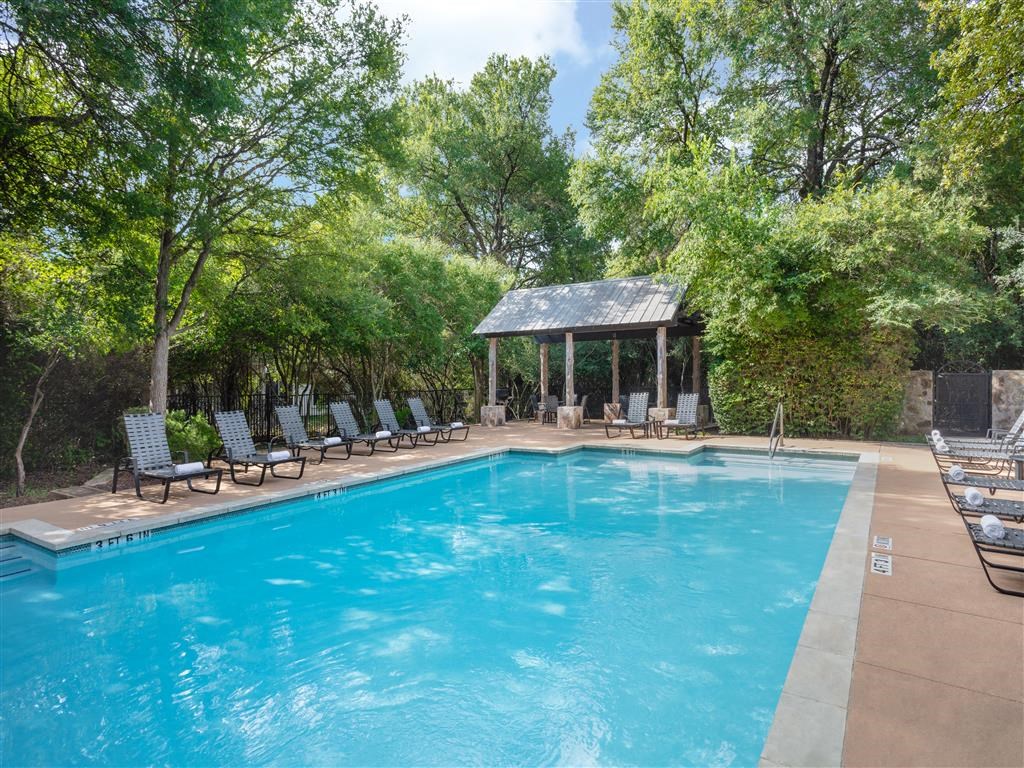 a pool with chairs and a gazebo next to a resort style pool