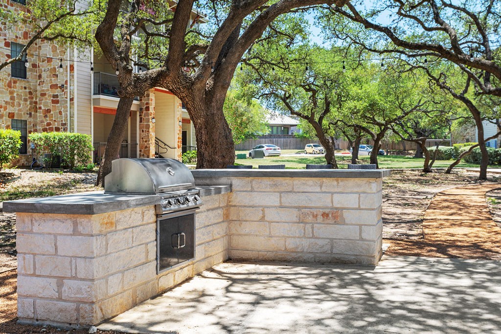 a stone barbecue grill in a courtyard with trees