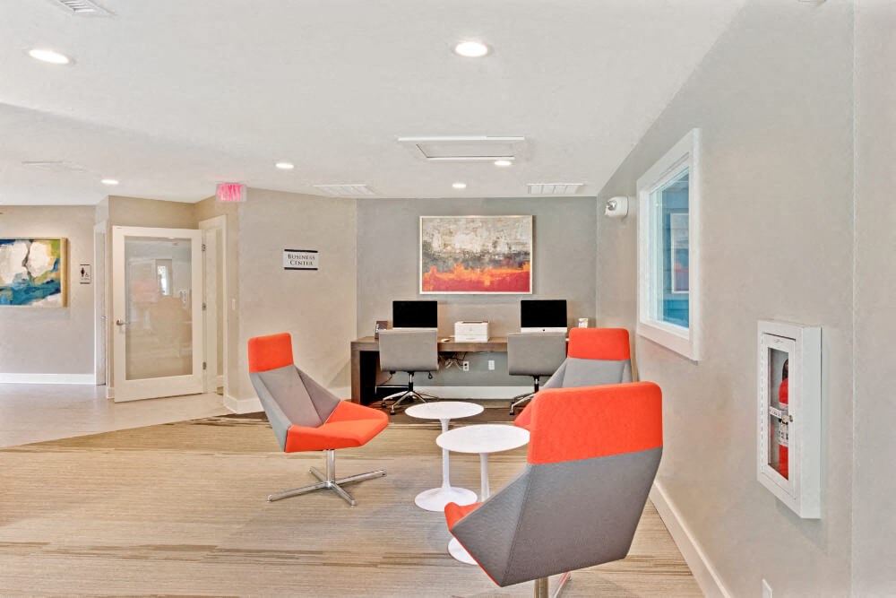 a waiting room with chairs and a table with computers