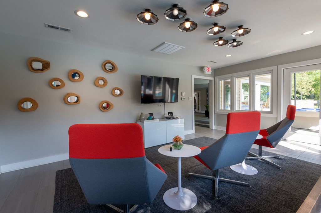 a lounge area with red chairs and a white table and a television