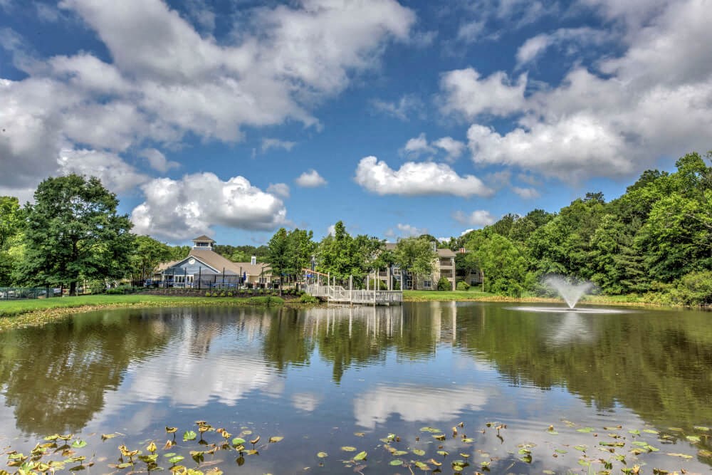 a lake with a fountain and a building in the background