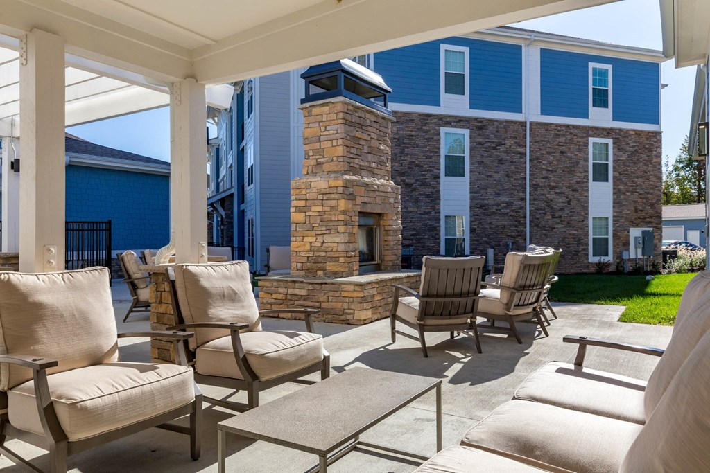 covered patio with chairs and a fireplace