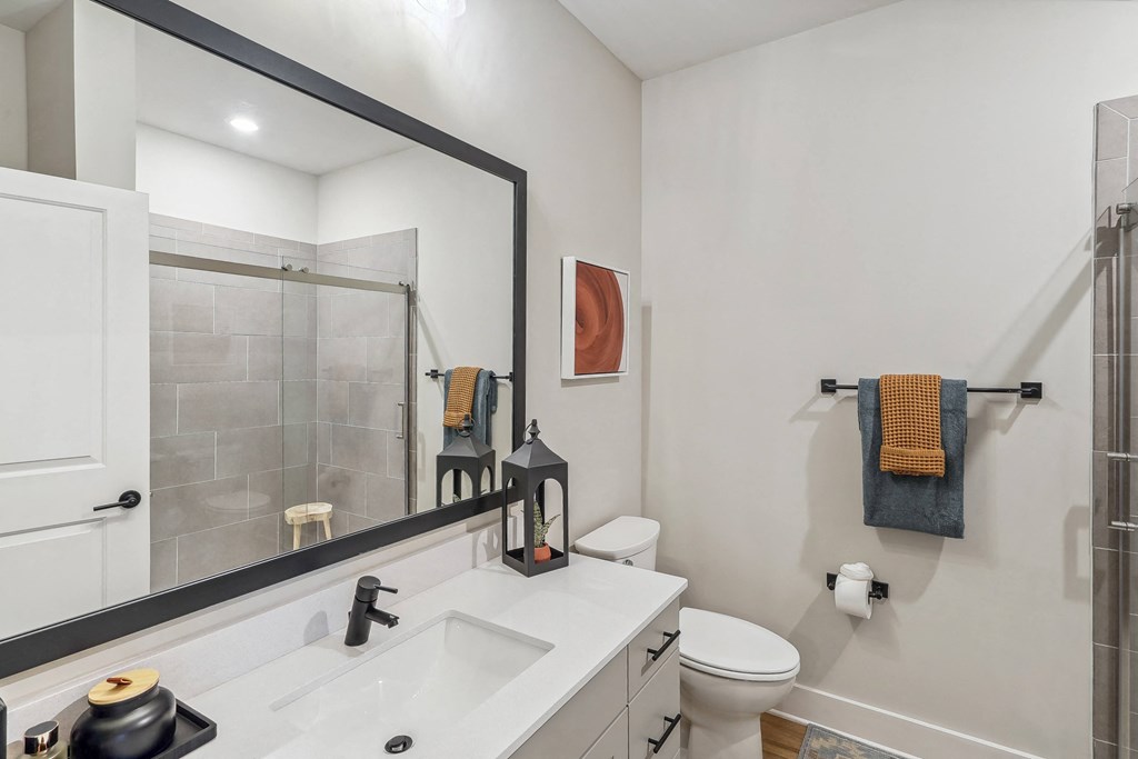 a white bathroom with a large mirror and a toilet and a shower