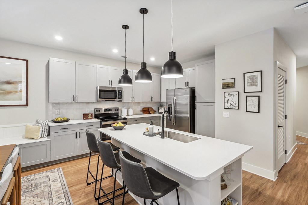 an open kitchen with a large white island with four chairs