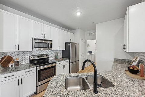 A kitchen with white cabinets and a granite countertop.