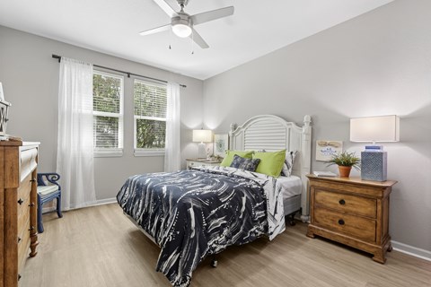 A bedroom with a bed, nightstand, and window.