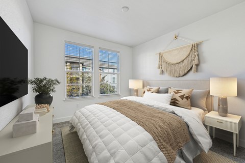 A bedroom with a large bed and a window with blinds.