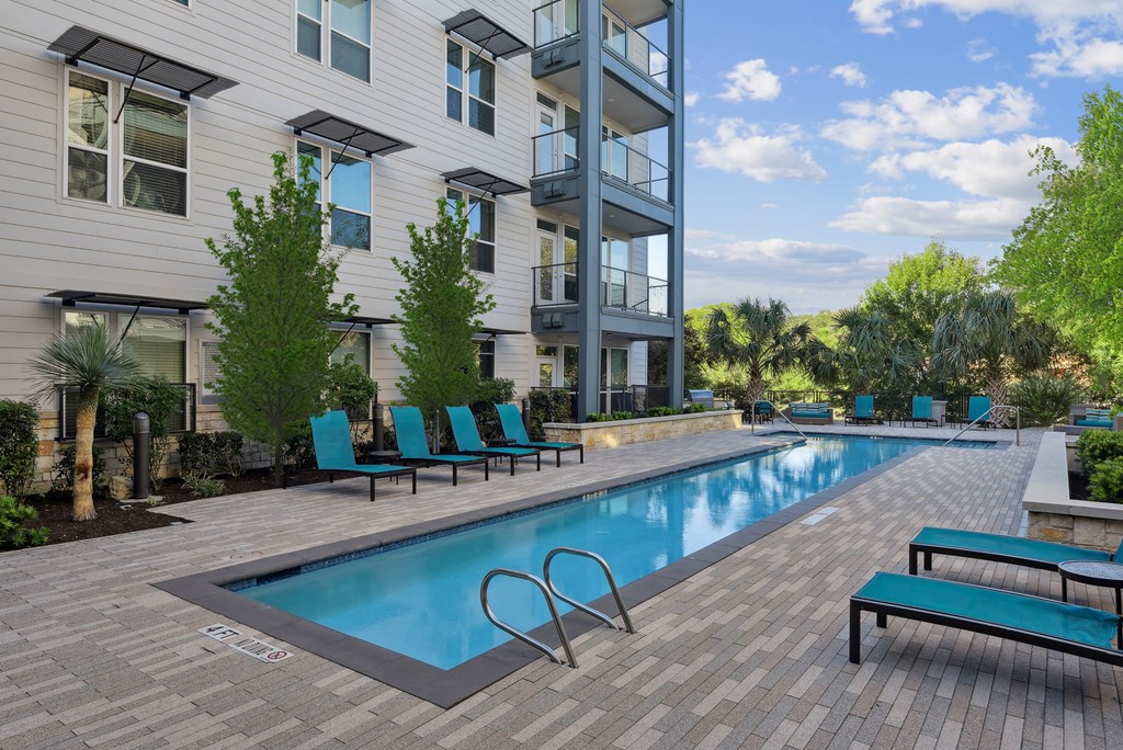 a swimming pool with blue chairs in front of a building