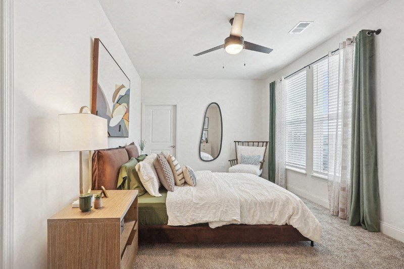 A bedroom with a bed, nightstand, and a ceiling fan.