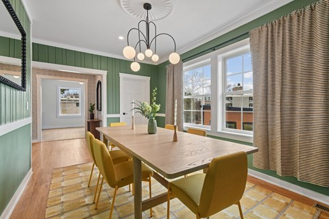 A dining room with a wooden table and yellow chairs.