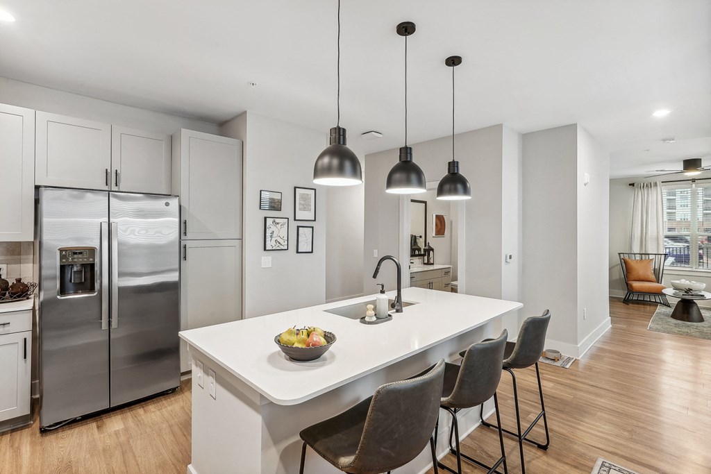 an open kitchen with a large island with chairs and stainless steel appliances