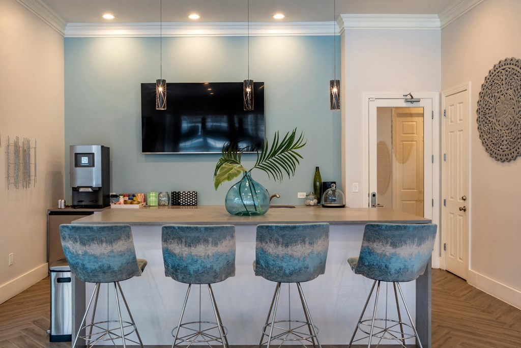 a kitchen with a bar with four stools and a tv on the wall