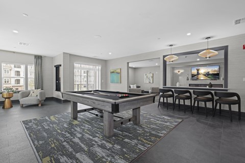 A billiard table is in the middle of a room with a grey carpet.