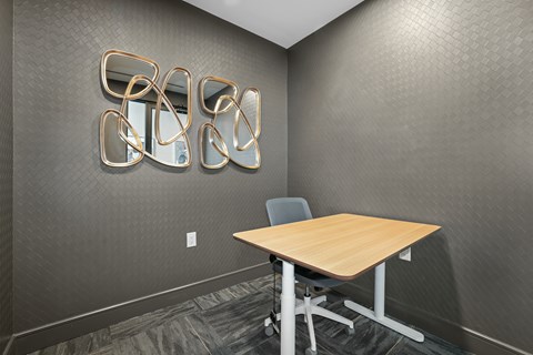 A private work pod with a wooden table and a grey chair.