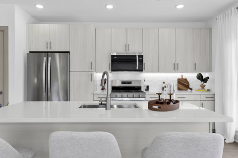 A modern kitchen with a white countertop and stainless steel appliances.