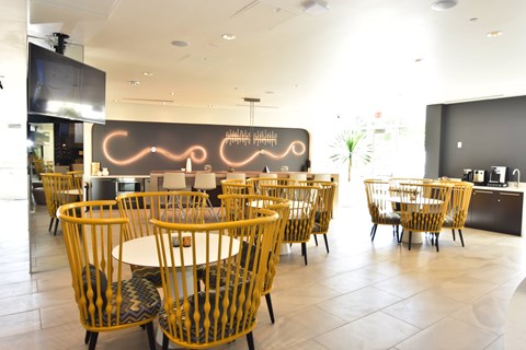A restaurant with tables and chairs and a neon sign on the wall.