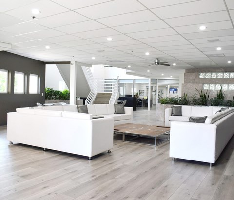 A spacious living room with white furniture and wooden flooring.