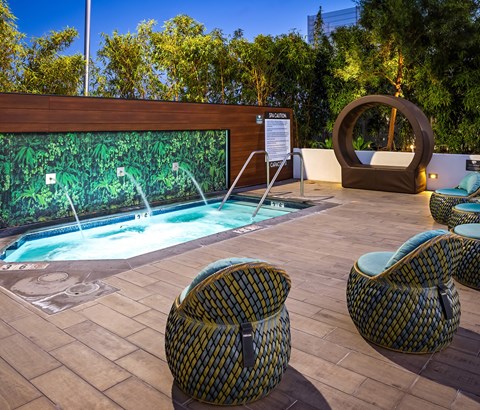 A pool with a waterfall and two chairs.