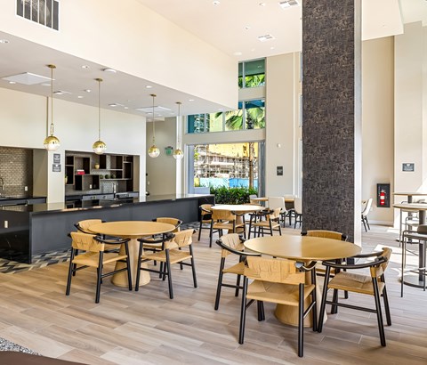 Community kitchen with dining tables and pendant lighting at Elements Apartments, Irvine