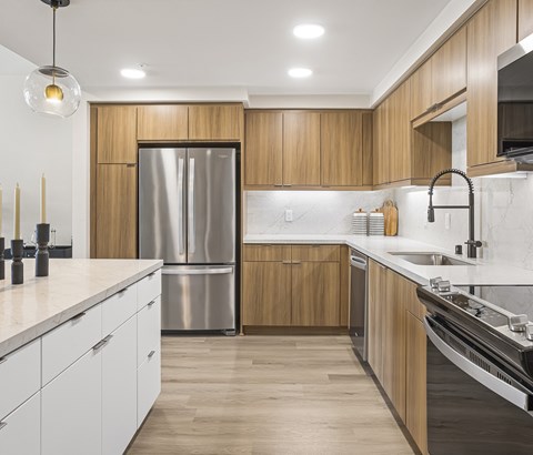 A modern kitchen with wooden cabinets and a stainless steel refrigerator.
