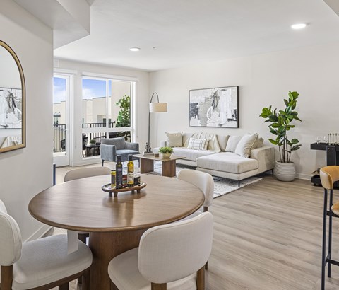 A modern dining room with a wooden table and white chairs.