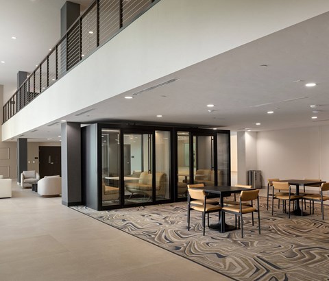 A modern dining area with a patterned carpet and a mix of wooden and metal chairs.