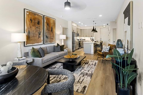 A modern living room with a grey sofa, a wooden table, and a large abstract painting on the wall.