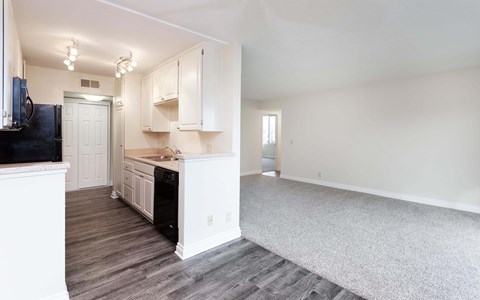 A kitchen with white cabinets and a black fridge.