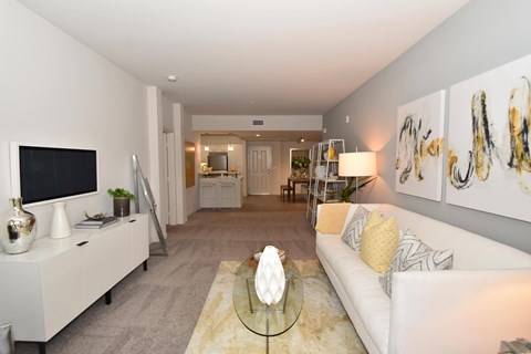 A living room with a white couch and a glass coffee table.