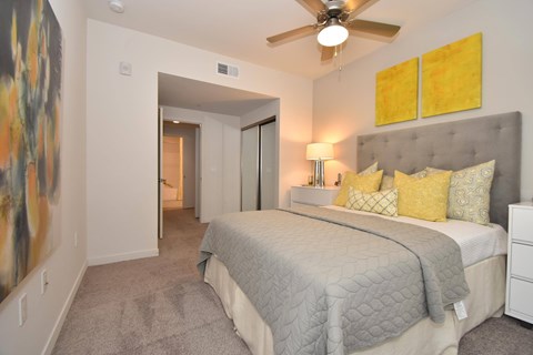 Bedroom with gray upholstered bed and yellow accents at Casa Mira View Apartments, California