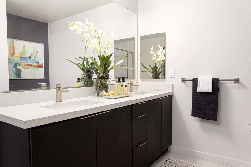 A bathroom with a white sink and a large mirror.