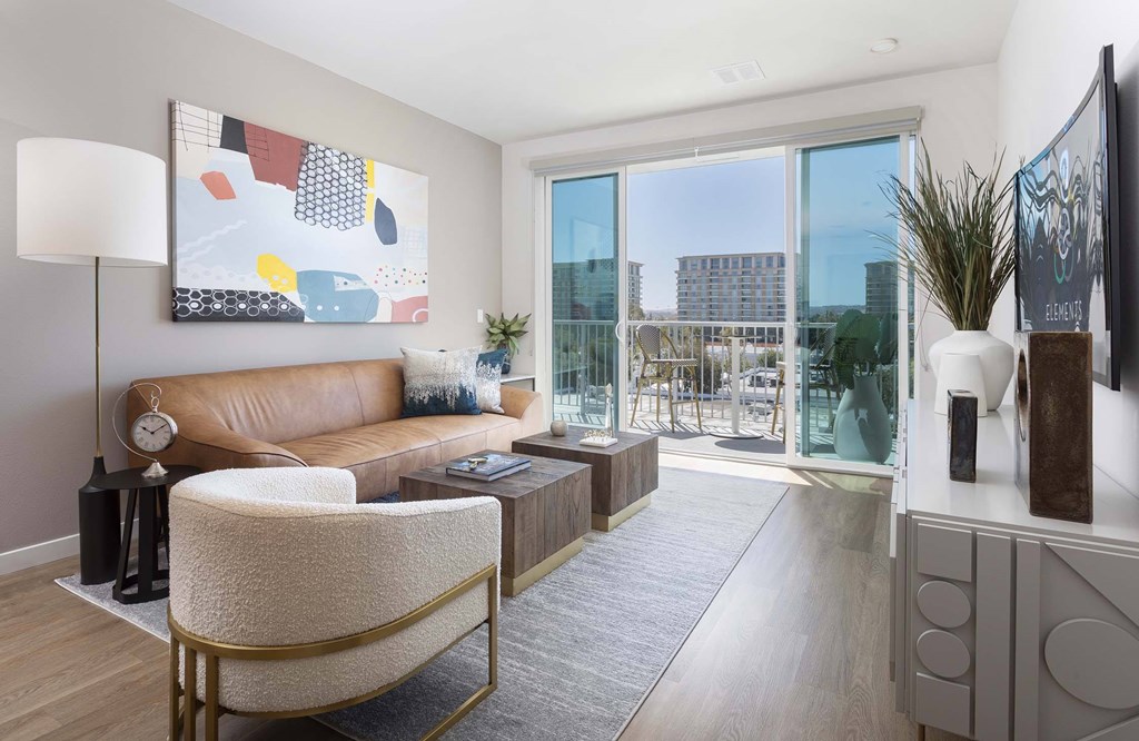 A living room with a brown leather couch, a white chair, and a large painting on the wall.