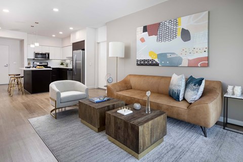 A modern living room with a brown sofa, a wooden coffee table, and a large abstract painting on the wall.