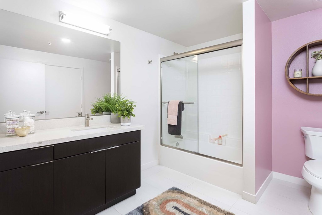 A bathroom with a pink wall and a white toilet.