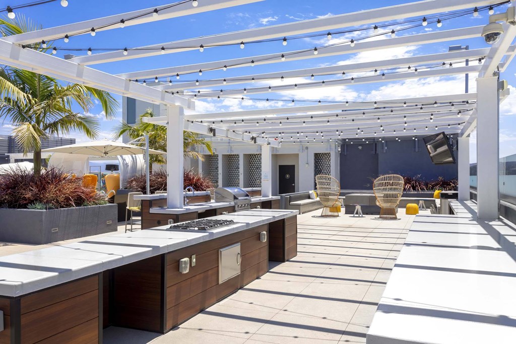 A modern outdoor kitchen with a white pergola and wooden countertops.