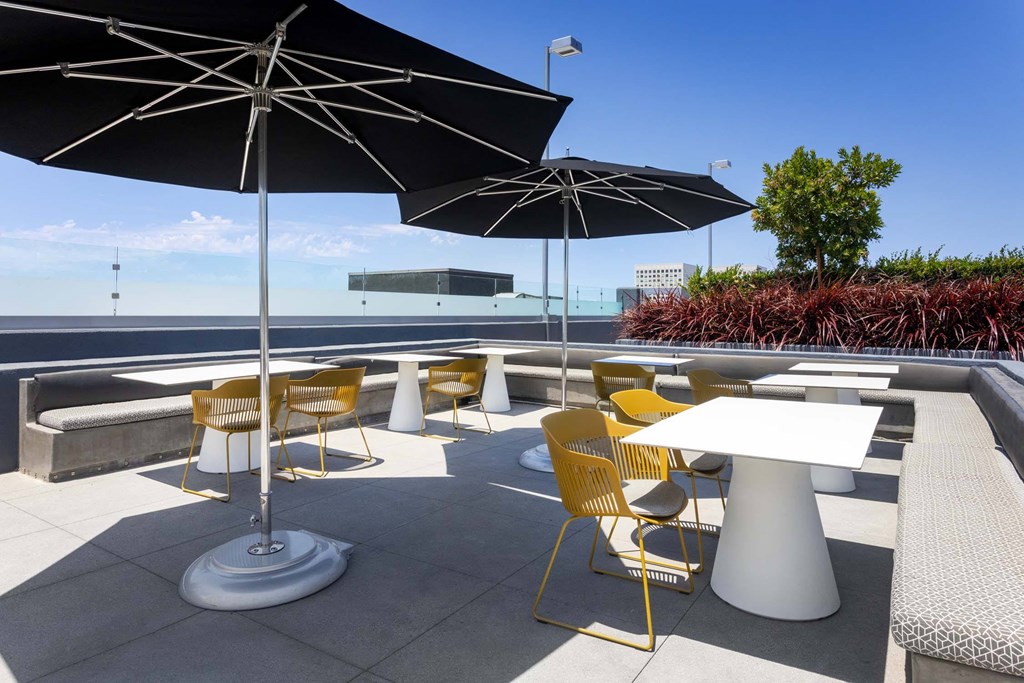 A patio with tables and chairs and umbrellas.