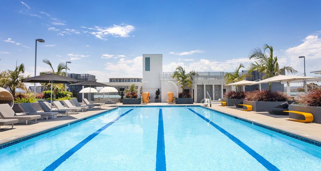 A large swimming pool with lounge chairs and a building in the background.