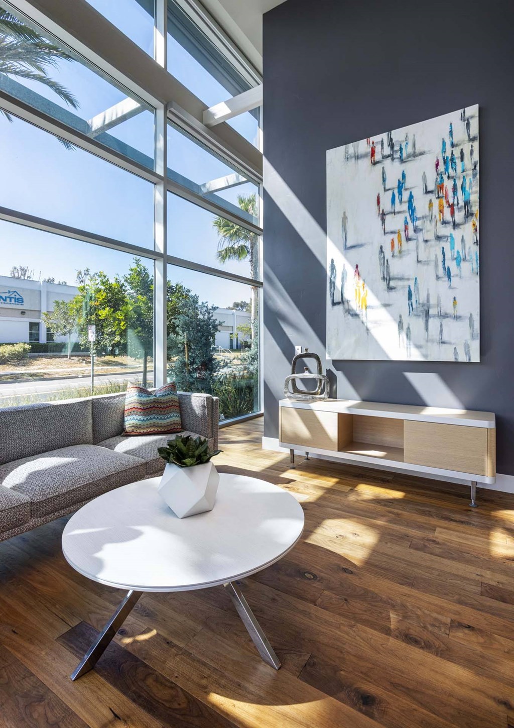A white table with a plant on it sits in front of a large window.